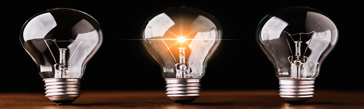 Three lightbulbs on table with middle lightbulb lit