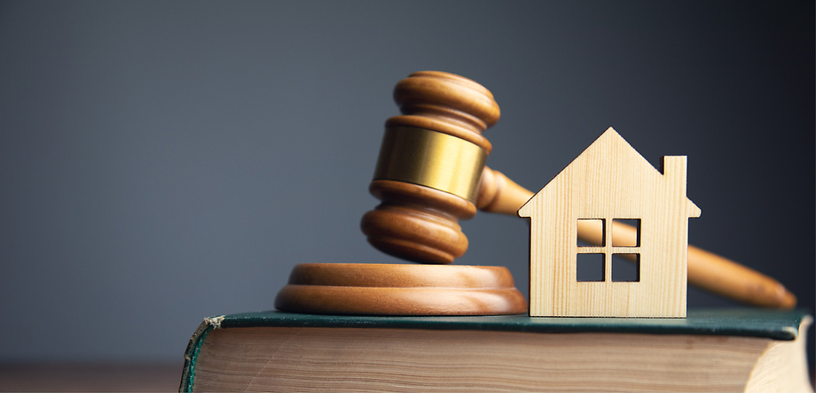 Gavel and wooden house figurine on book